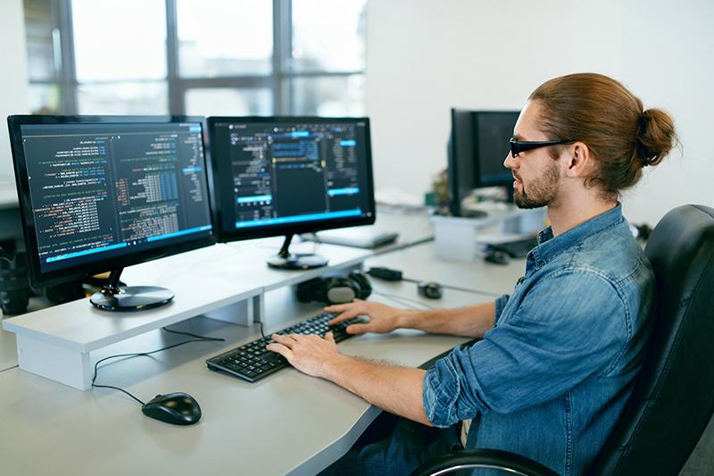 Programming. 在IT办公室工作的人，坐在办公桌前写代码. 软件开发公司的程序员，在项目中输入数据代码. High Quality Image.